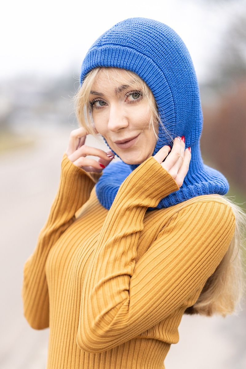 A woman wearing a blue knitted balaclava over her head and neck