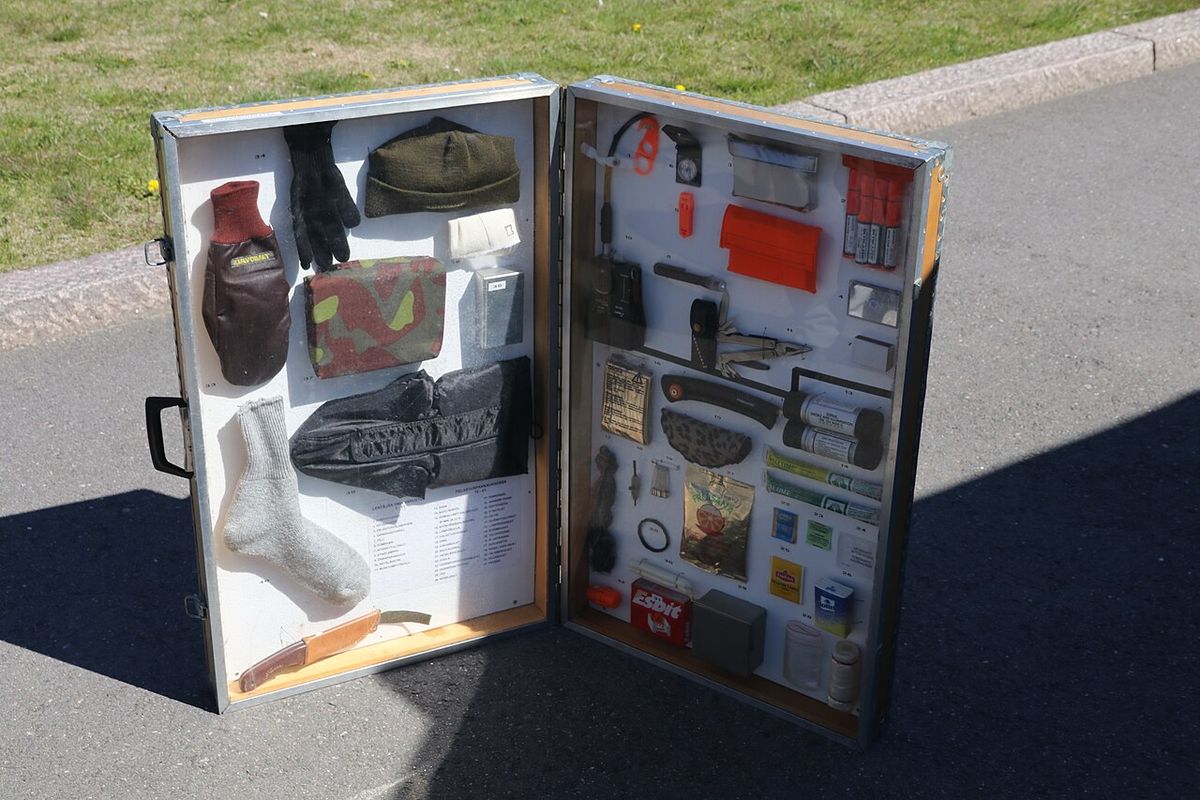 An aircrew survival kit opened to show first aid, fire, signal, water and food items