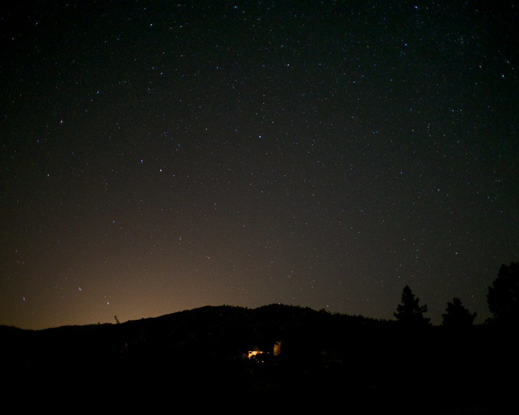 A night sky full of stars over a dark ridge