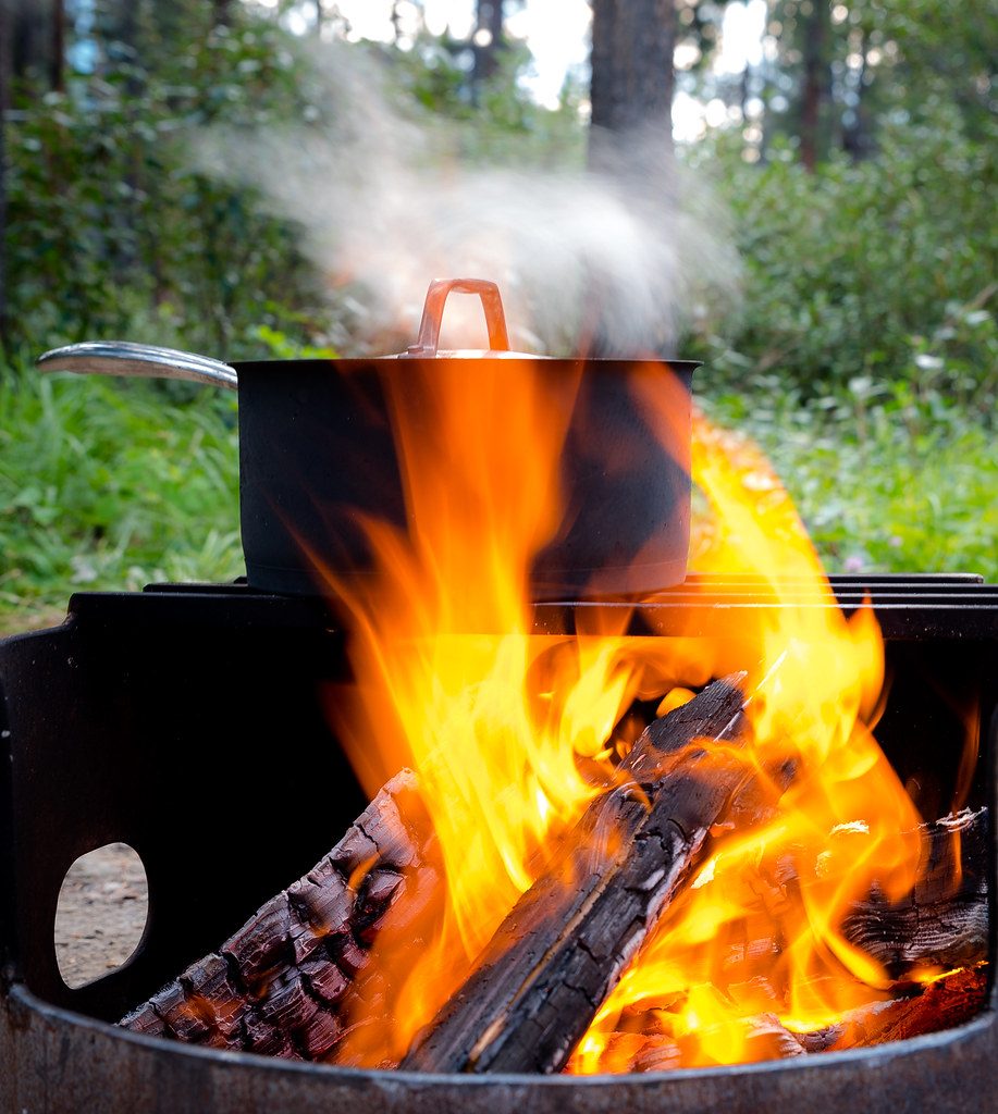 A pot of water boiling over a campfire