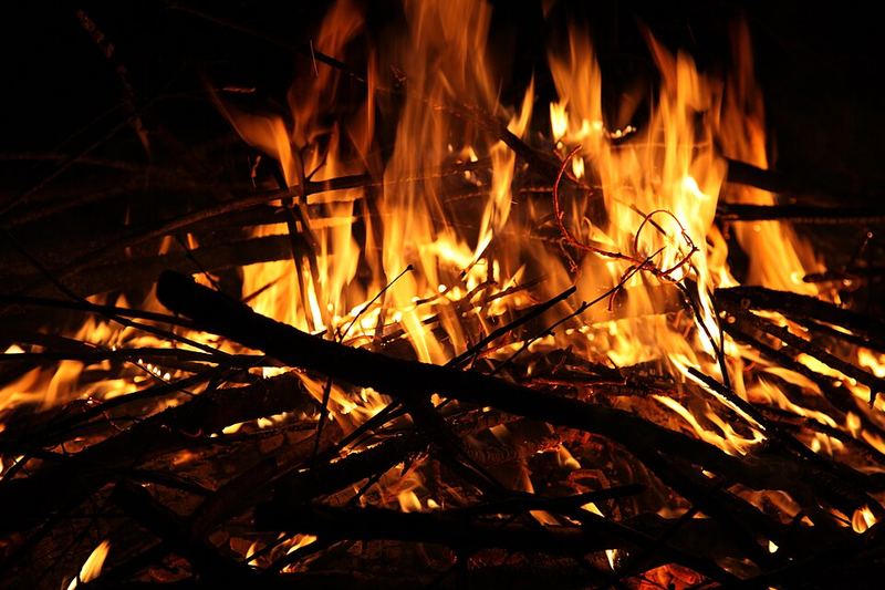 A bright campfire of dry branches burning at night