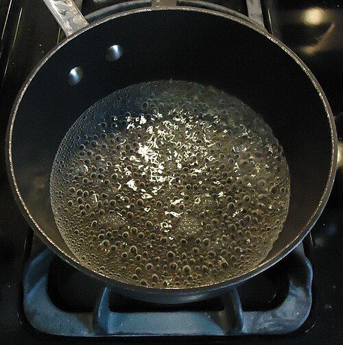 Water at a full rolling boil in a metal pot