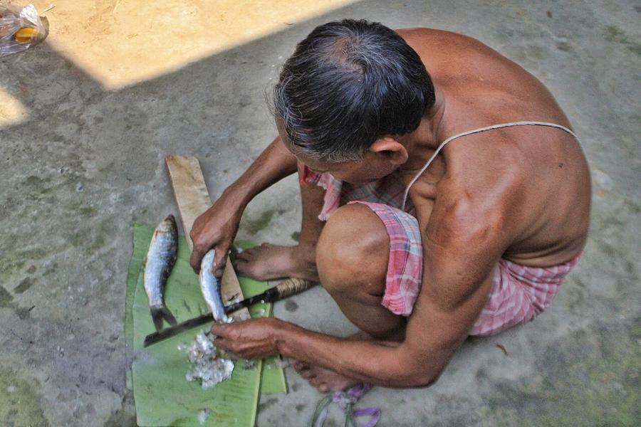 A man scaling a fish with a knife